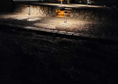 Backyard at night with patio lights and a stone retaining wall.