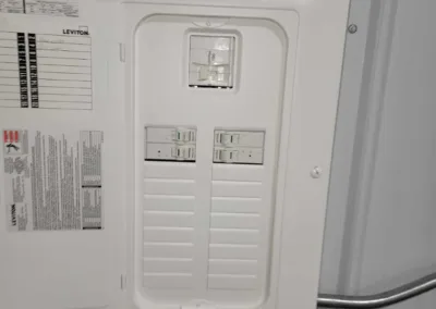 Electrical panel with an open cover revealing circuit breakers in a metal enclosure.