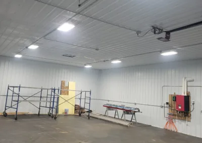 An empty industrial room with scaffolding, a workbench, and construction materials.