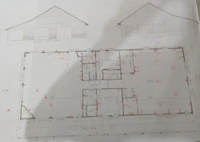 Hand-drawn architectural house plan with front and side elevations, including dimension annotations and layout details.