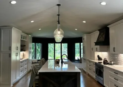 Modern kitchen with white cabinetry, hardwood floors, and a central island under a pendant light.