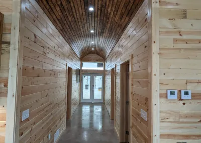 Interior hallway with wooden walls and arched ceiling featuring recessed lighting.