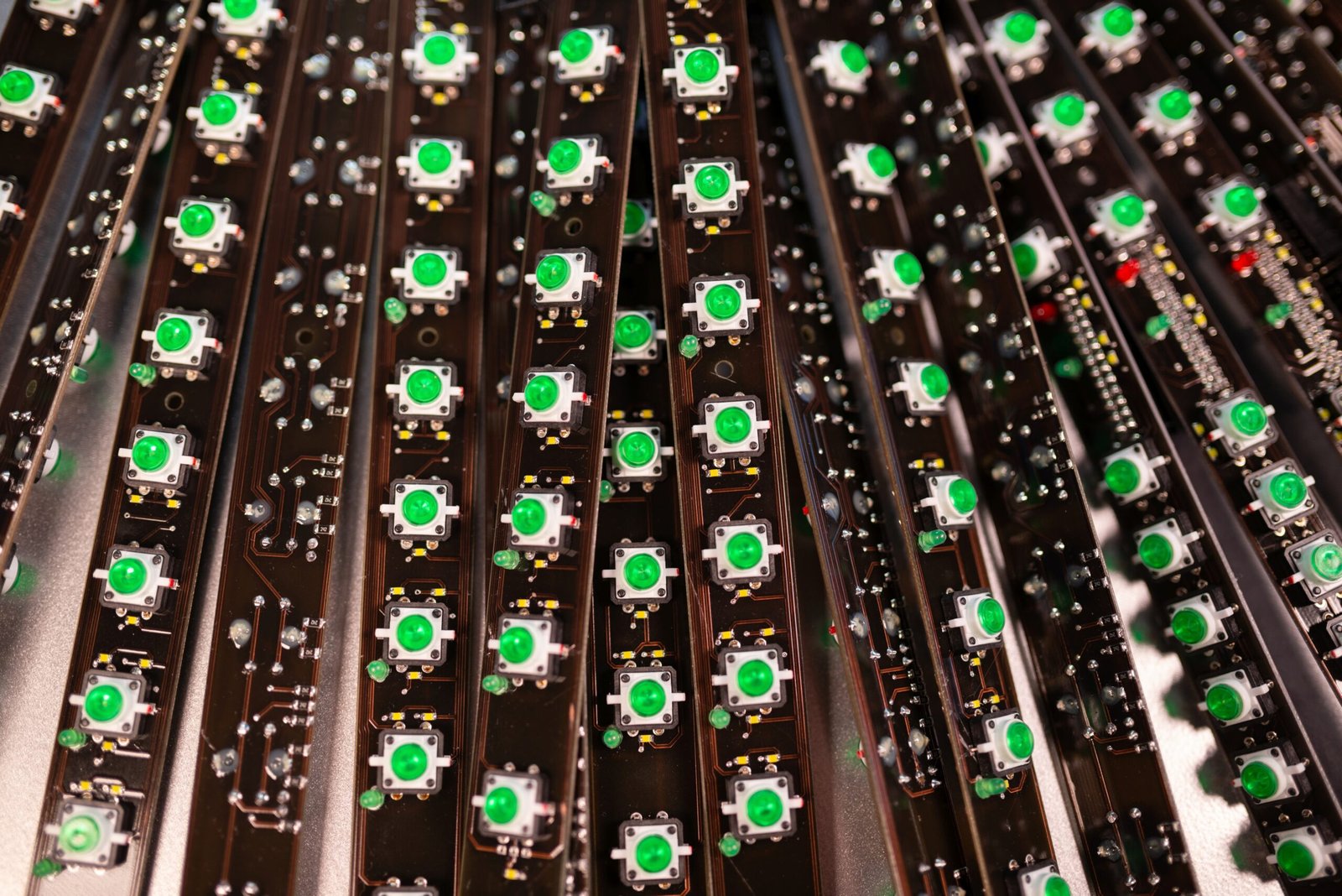 Rows of green circuit boards with various electronic components and black wiring, resembling a tech manufacturing setup.