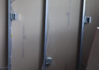Exposed metal wall studs with electrical boxes and wiring, partially covered by drywall panels in a construction area.